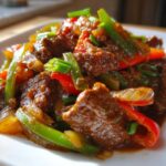 Close-up of tender beef strips coated in rich sauce with sliced green and red peppers, part of the amazing 30-Min pepper steak.
