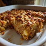 A close-up of a square serving being lifted from a baked apple cinnamon oatmeal dish in a white casserole.