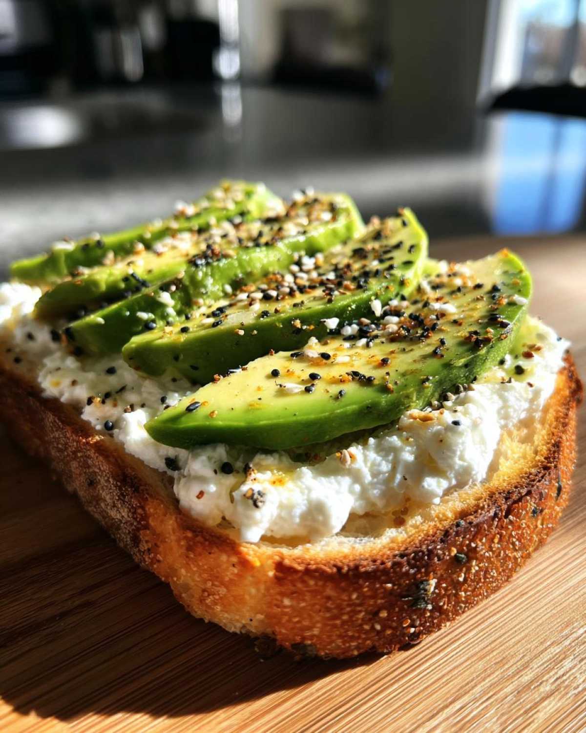 Close-up of avocado slices on cottage cheese toast topped with everything bagel seasoning.