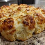 Close-up of baked Hawaiian roll garlic bread topped with melted, browned mozzarella cheese.