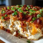 Close-up of a rich, creamy popper dip slice topped with crispy bacon bits and fresh green onions.