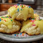 A stack of fluffy Italian ricotta cookies topped with thick yellow glaze and colorful sprinkles.