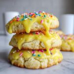 Three stacked Italian ricotta cookies topped with bright yellow glaze and colorful sprinkles.
