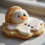 A close-up of a melted snowman cookie featuring a marshmallow head, cookie hat, and white icing puddle.