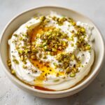 Close-up of creamy whipped feta dip drizzled with honey and topped with chopped pistachios.