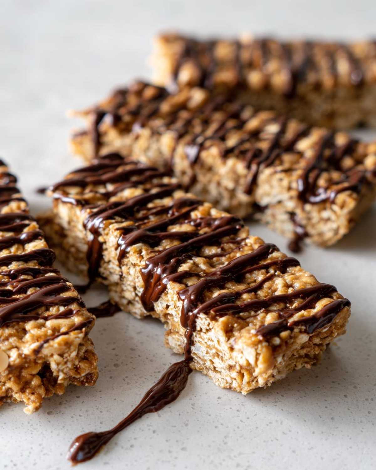 Close-up of homemade protein bars made with oats, drizzled generously with melted dark chocolate.