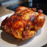 A whole chicken cooked to perfection in an air fryer, featuring crispy, golden-brown skin, ready to serve.