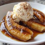 Close-up of caramelized bananas foster topped with vanilla ice cream and cinnamon.