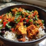 Close-up of a delicious chicken burrito bowl featuring seasoned chicken over white rice with black beans, diced tomatoes, and cilantro.