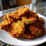 A close-up, appetizing pile of golden brown, crispy Fried Pickles served on a white plate.