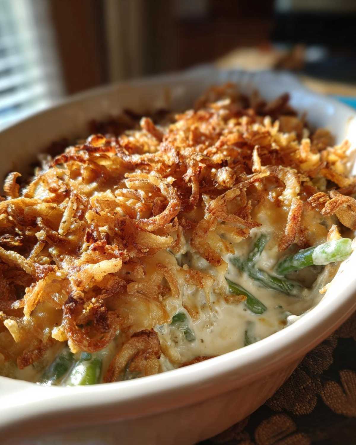 Close-up of a creamy green bean casserole topped generously with crispy fried onions.