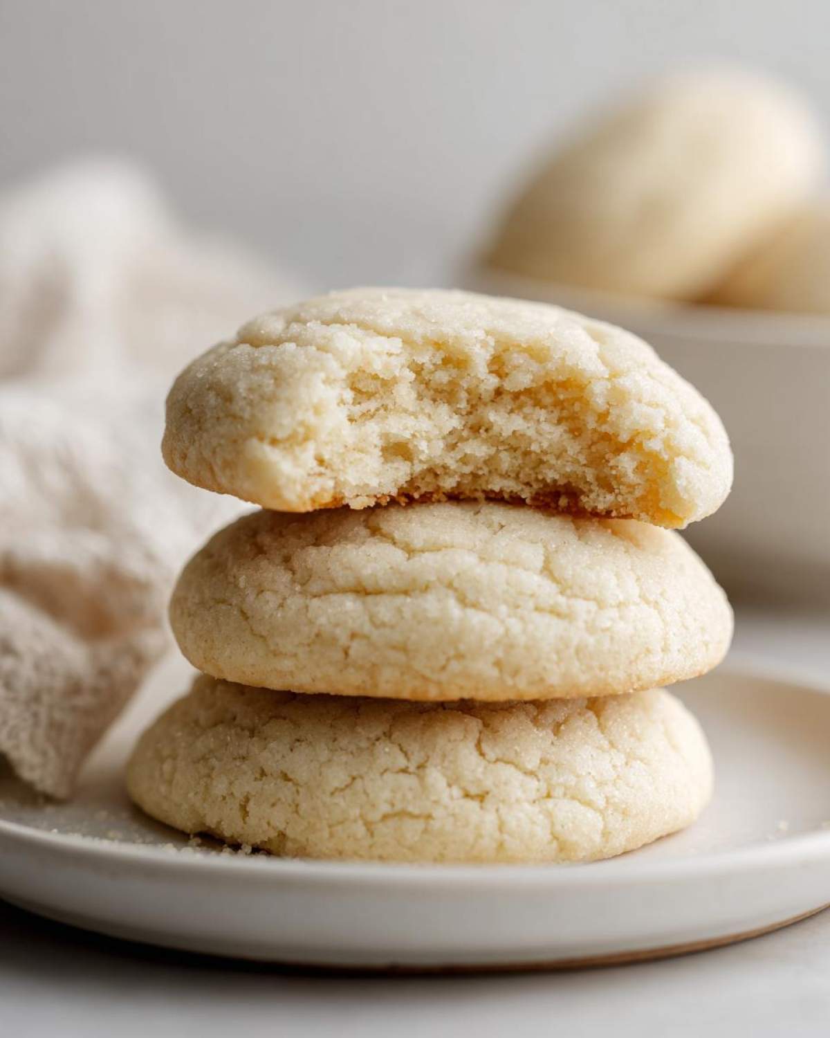 A stack of three amazing soft sugar cookies, with the top one having a bite taken out to show the texture.