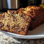 Close-up of two slices of moist chocolate chip banana bread on a white plate.