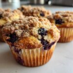 Close-up of a freshly baked blueberry muffin with a thick, sugary crumb topping.