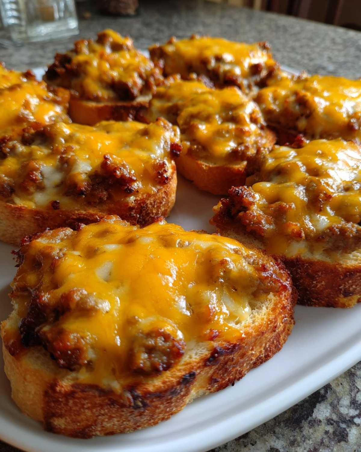 Close-up of several toasted bread slices topped with savory meat mixture and melted cheddar cheese, ready to serve as a hanky panky recipe appetizer.