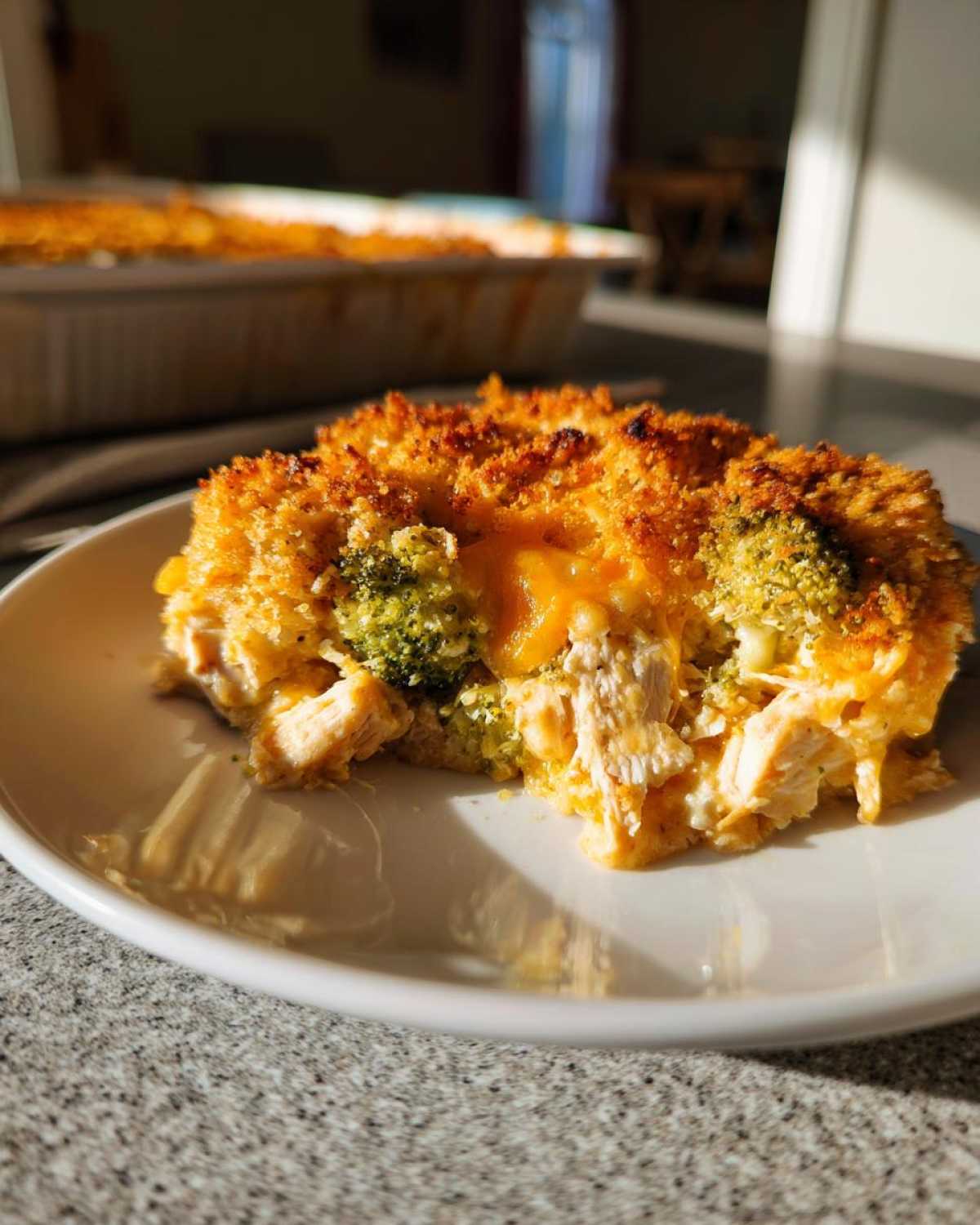 A close-up serving of Chicken Divan with a golden, crunchy topping and visible chunks of chicken and broccoli.