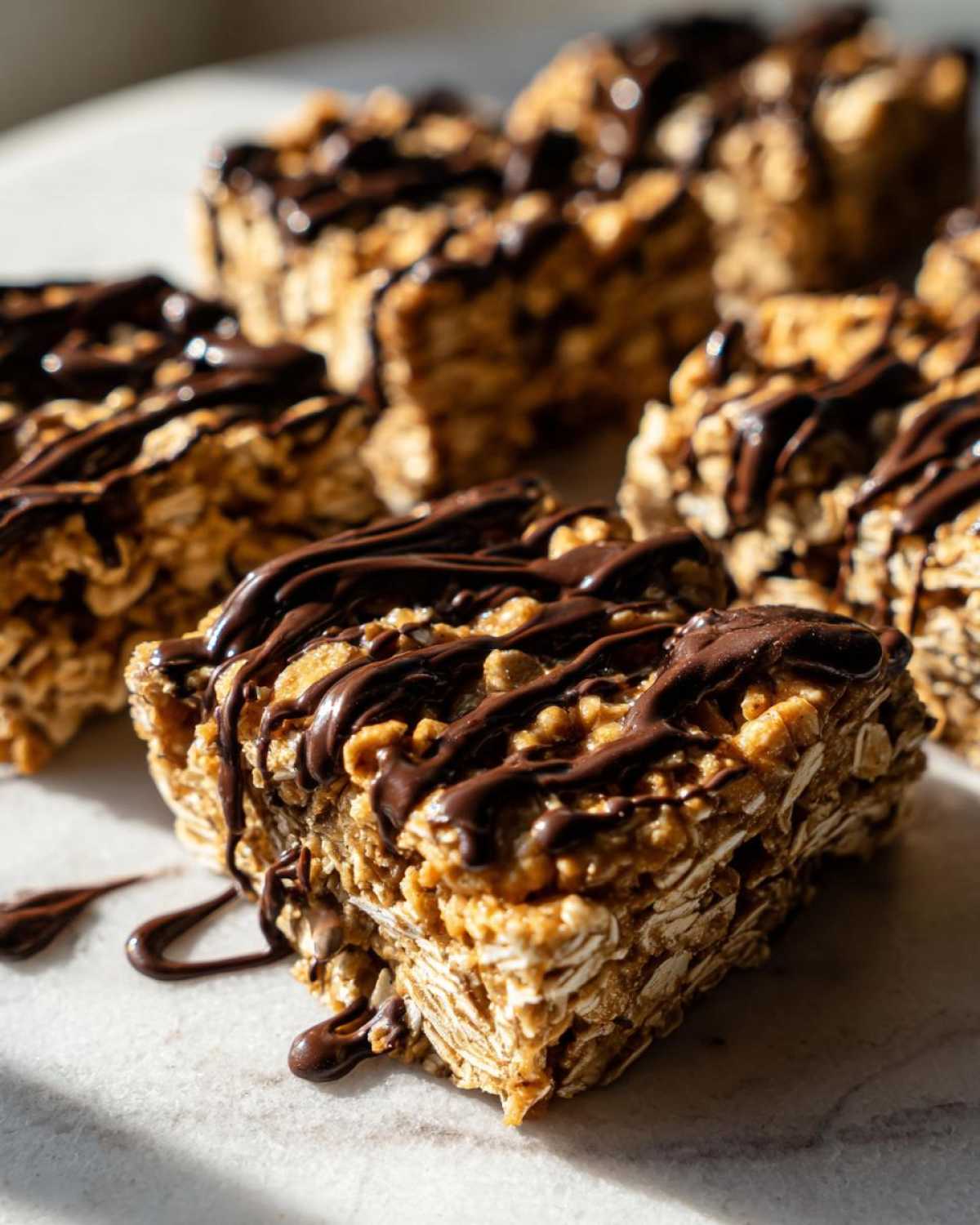 Close-up of chewy, homemade protein bars made with oats and drizzled generously with dark chocolate.