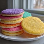 Stack of colorful sugar cookies topped with sparkling sugar, demonstrating the sugar cookie icing that hardens.
