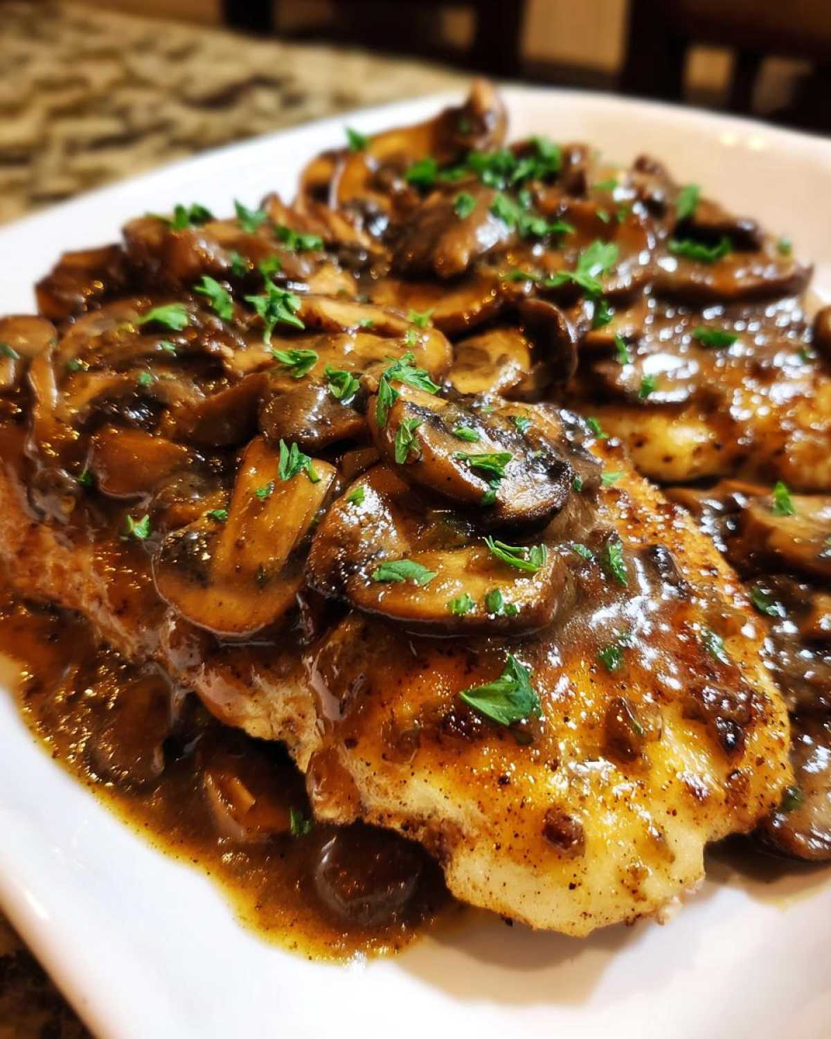Close-up of pan-seared chicken breasts smothered in rich, dark mushroom sauce for chicken marsala.