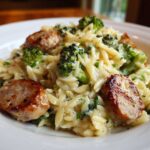 Close-up of creamy chicken sausage and broccoli orzo pasta mixed with a light sauce and garnished with parsley.