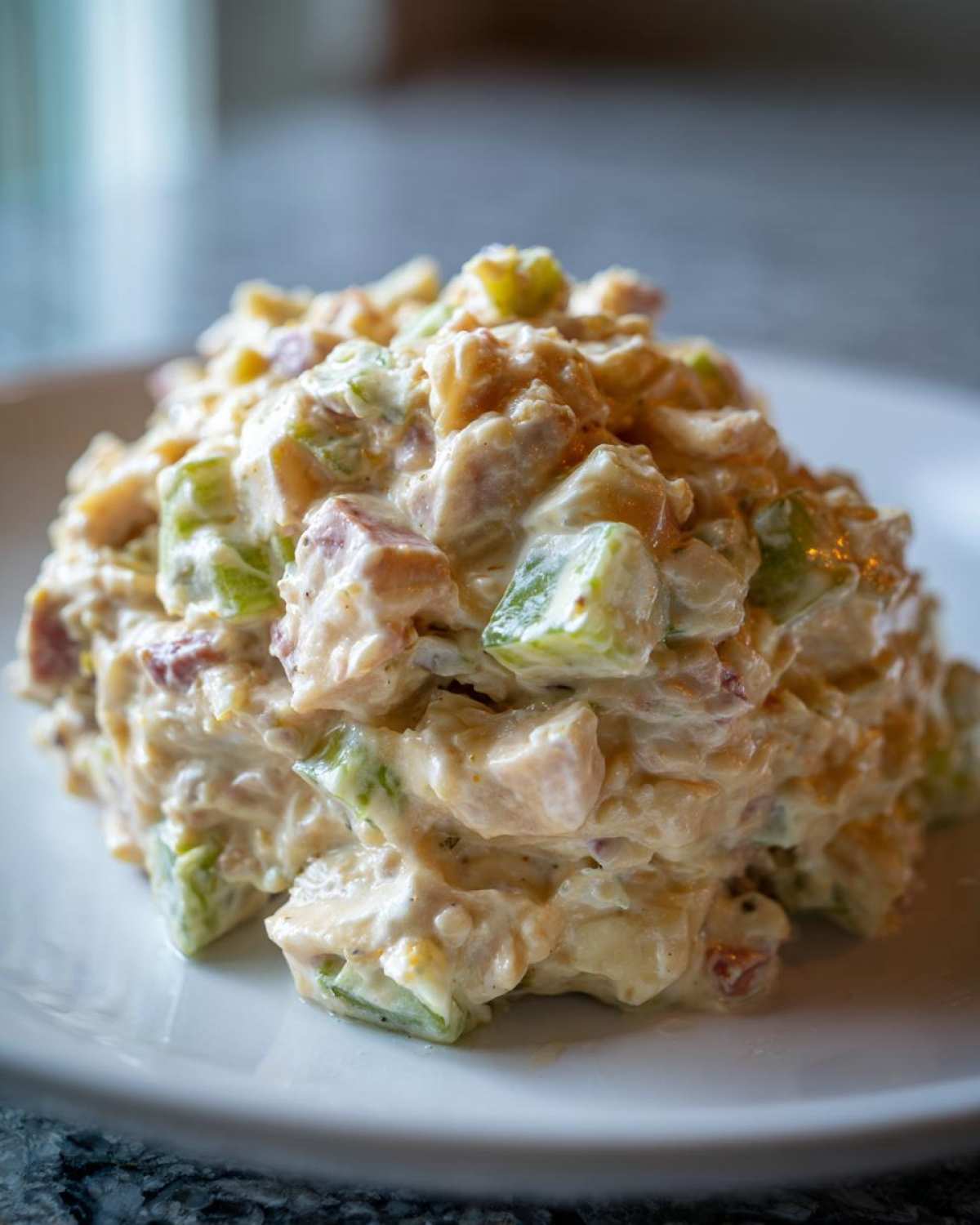 A close-up, appetizing mound of creamy ham salad recipe, featuring diced ham and green celery chunks.