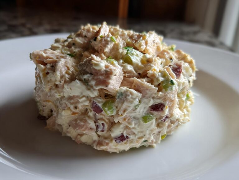 A mound of creamy ham salad recipe mixture served neatly on a white plate.