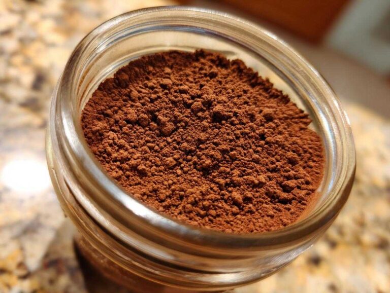 Overhead close-up view of rich brown hot cocoa mix powder filling a clear glass jar.