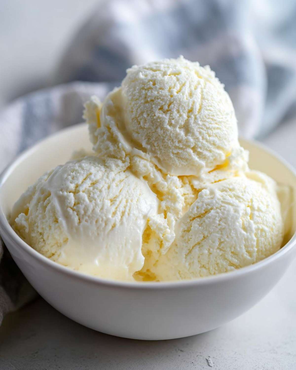 Three scoops of creamy vanilla protein ice cream served in a white bowl.