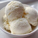 Four scoops of creamy, white protein ice cream served in a white bowl.