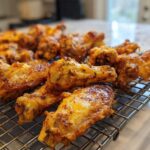 Close-up of golden brown, seasoned crispy baked chicken wings resting on a wire cooling rack.