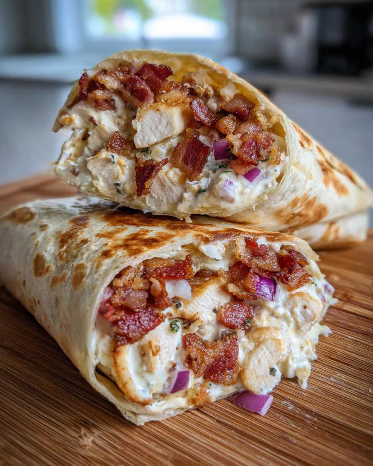 Two halves of a crispy chicken bacon ranch wrap showing the filling of chicken, bacon, and creamy ranch sauce.