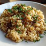 A close-up of fluffy french onion butter rice topped with caramelized onions and fresh chopped parsley.
