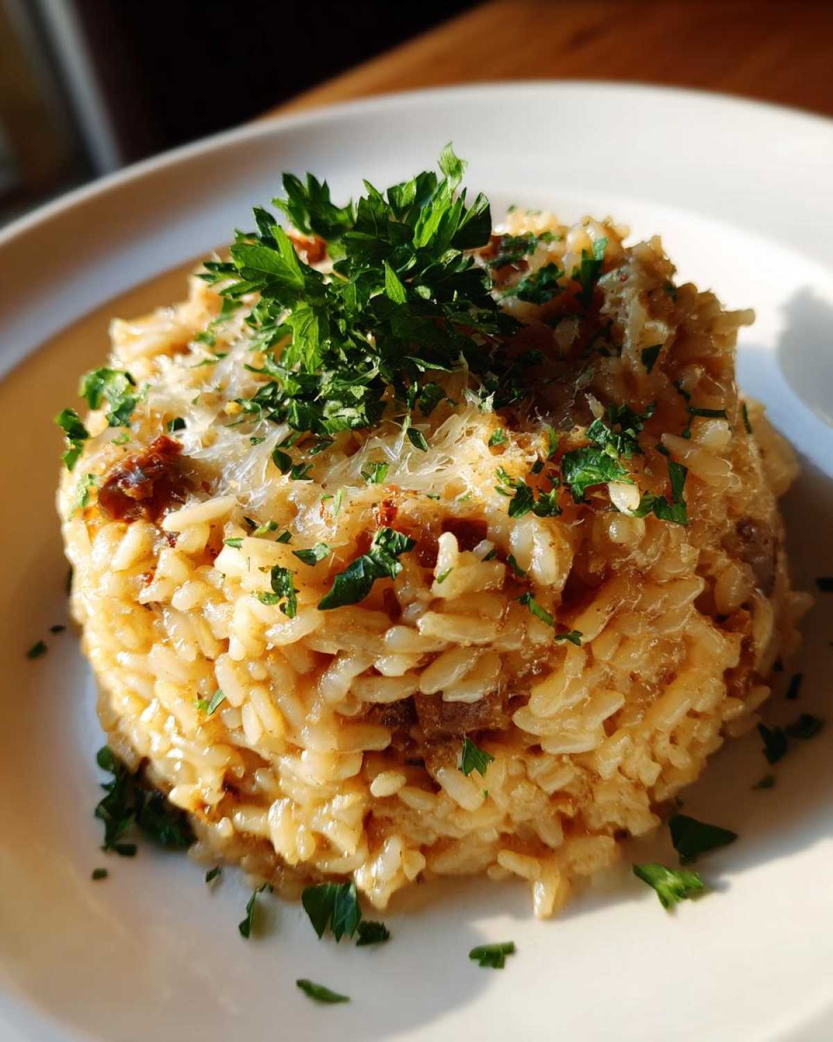 A mound of creamy french onion butter rice topped with grated cheese and fresh parsley.