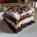 A layered slice of brownie refrigerator cake with a fudgy chocolate layer and whipped topping.