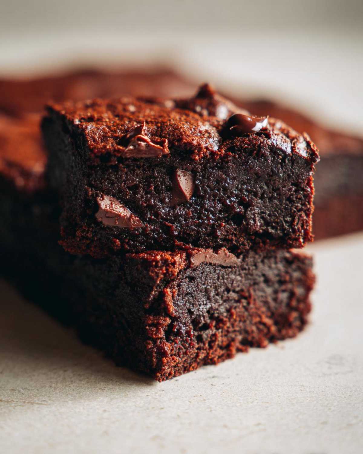 Close-up of two fudgy sweet potato brownies stacked, showing rich chocolate color and melted chips.