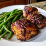 Three pieces of glazed chicken served next to a generous portion of bright green beans, showcasing the finished chicken and green beans dish.