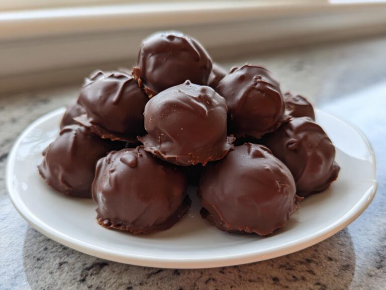 A stack of rich, chocolate-covered Oreo balls piled high on a small white plate.