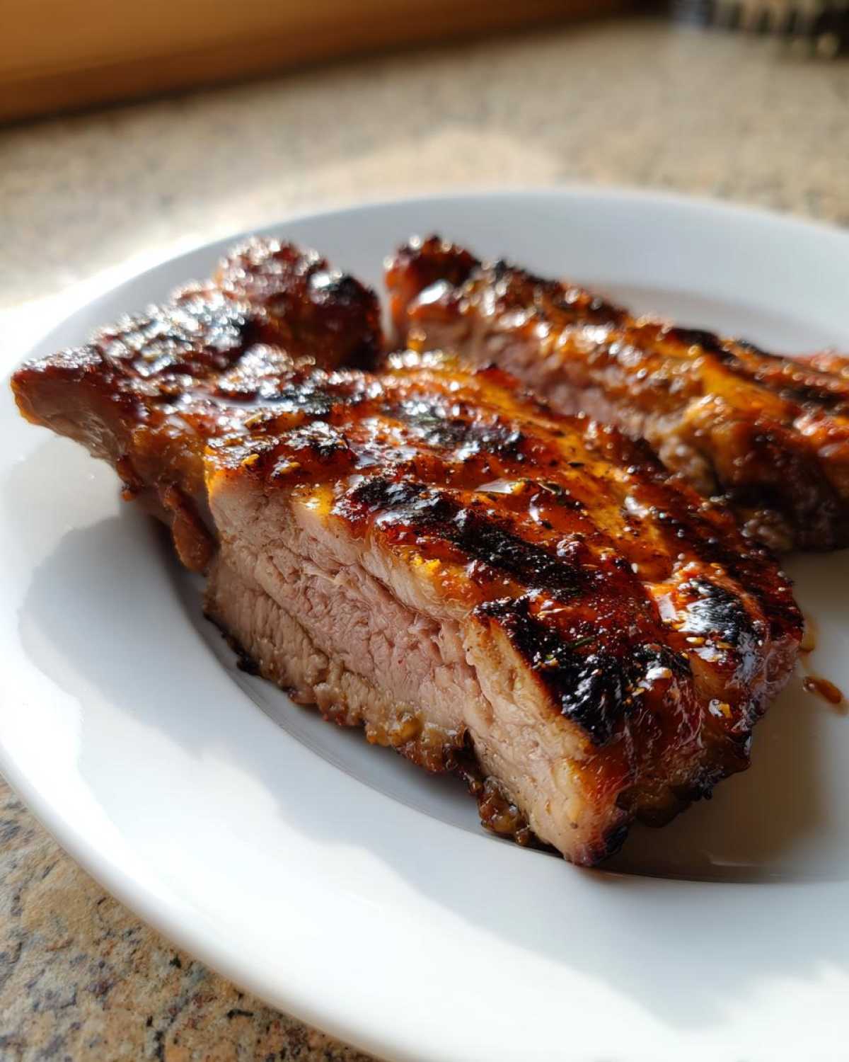 Close-up of a thick, juicy pork steak recipe cut in half, showing tender pink meat and a caramelized, dark glaze.