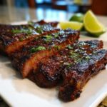 Close-up of perfectly grilled, sliced steak coated in a rich glaze, garnished with cilantro, showing the results of the Carne asada marinade.