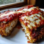 Cross-section of crispy keto chicken parmesan topped with marinara sauce and melted mozzarella cheese.