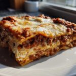 A thick, golden-brown slice of Lasagna with Cottage Cheese featuring layers of pasta, meat sauce, and creamy white filling.