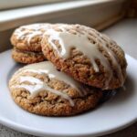 Close-up of stacked maple brown sugar cookies drizzled with a light glaze on a white plate.