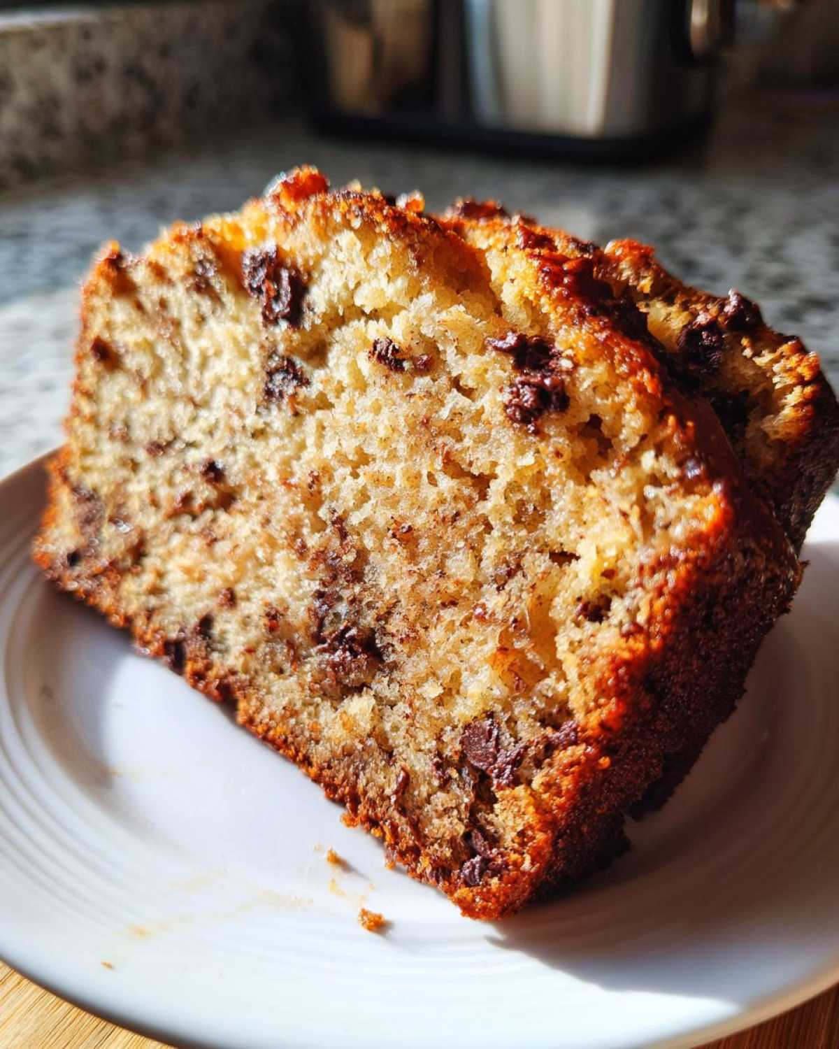 Close-up of two moist slices of chocolate chip best banana bread on a white plate.