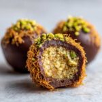 Close-up of a no-bake dubai chocolate balls cut in half showing the crumbly filling and crispy outer layer.