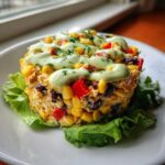 A molded serving of southwest chicken salad featuring corn, black beans, and red peppers, topped with a creamy green dressing.