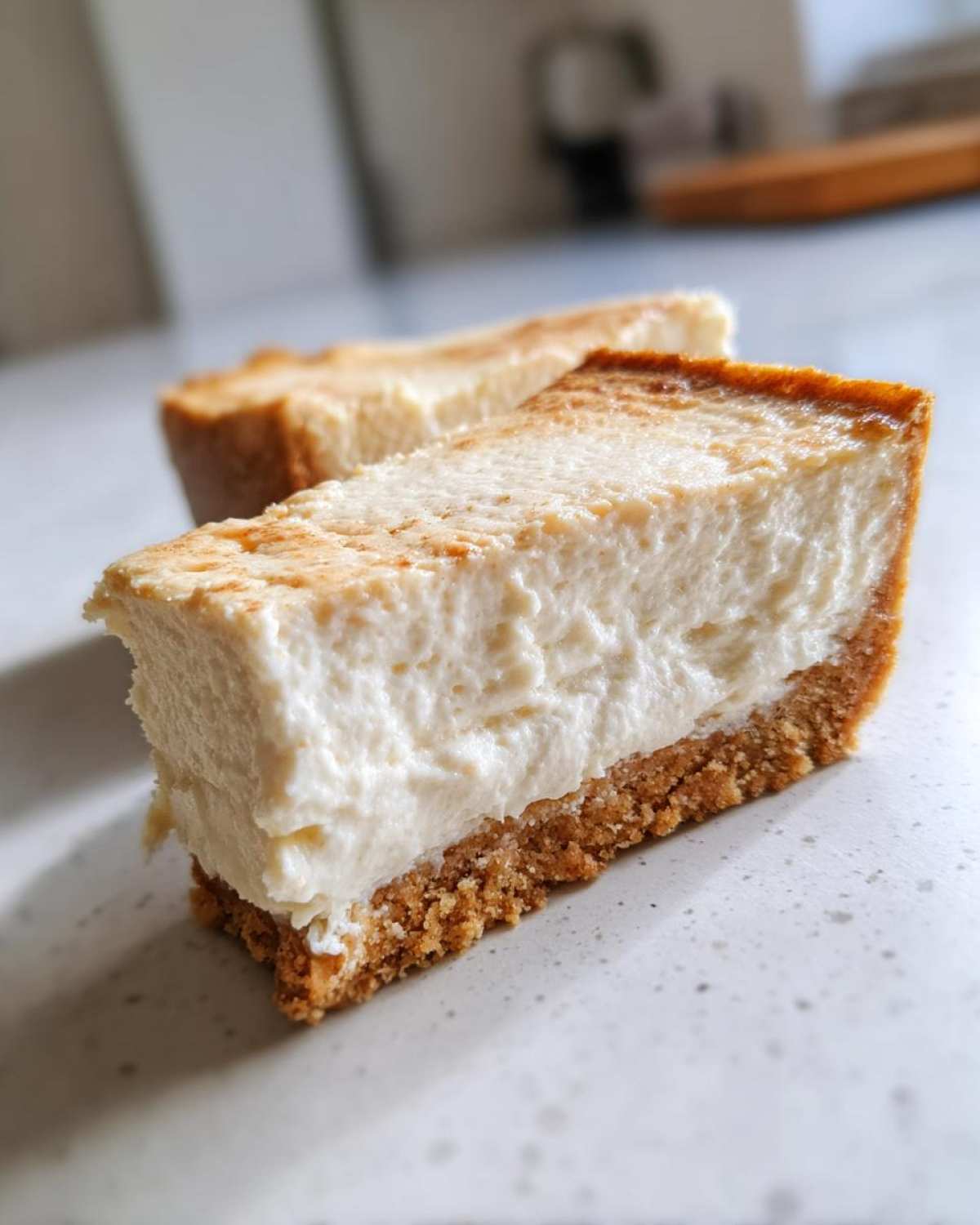 Close-up of a thick slice of creamy Protein Cheesecake showing the dense filling and graham cracker crust.