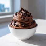 A generous swirl of rich chocolate dip topped with mini chocolate chips in a white bowl.
