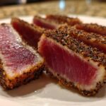 Close-up of perfectly cooked Seared Ahi Tuna slices showing a dark pepper crust and rare, deep red center.