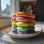 A stack of five brightly colored cookies topped with thick, vibrant sugar cookie icing that hardens, sitting on a white plate.