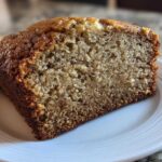 Close-up of a moist slice of sugar free banana bread showing its crumb texture on a white plate.
